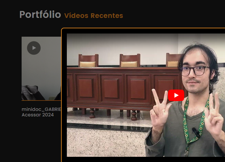 Imagem parcial de uma modal com vídeo e borda laranja em frente a uma página de portfólio de vídeos de cor preta.